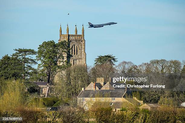 Rockwell B-1 Lancer bomber takes off on a sortie from RAF Fairford over the Cotswold village of Kempsford and the village church of St. Mary the...