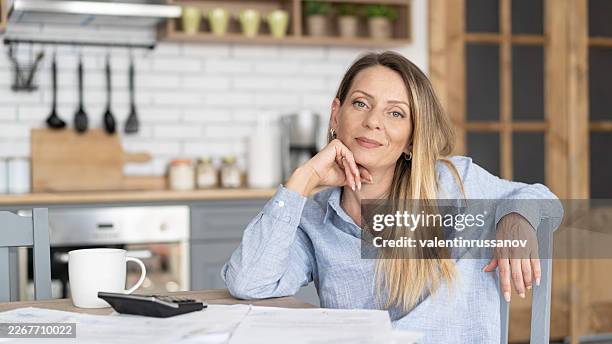 woman managing household bills, calculating expenses in kitchen - beak stock pictures, royalty-free photos & images
