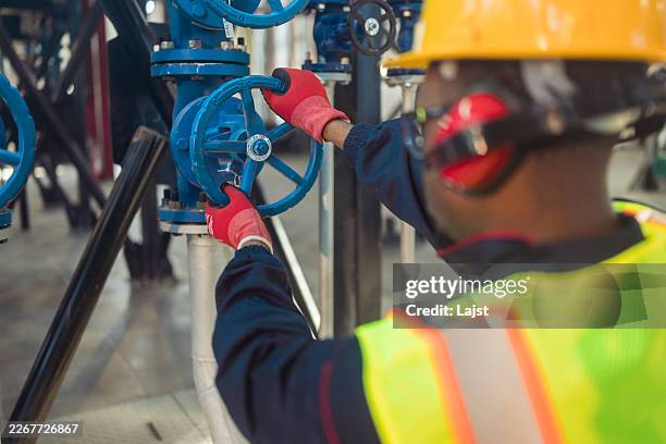 industrial worker operating a valve in plant construction - anatomical valve stock pictures, royalty-free photos & images