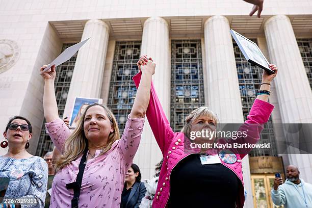 Amy Neville, left, and Lori Schott, raise hands while holding photographs of their children who passed after hearing the verdict outside the Los...