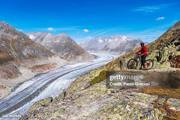 tourist with mountain bike admires glacier, switzerland - aletsch glacier stock pictures, royalty-free photos & images