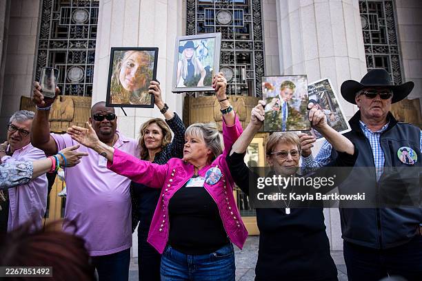 The family of victims raise photographs of their loved ones who passed away after hearing the verdict outside the Los Angeles Superior Court during...