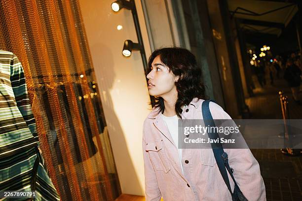 young woman window shopping at night in city - window shopping stock pictures, royalty-free photos & images