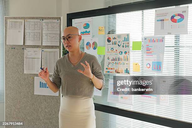 professional asian woman presenting data and business charts in a modern office meeting. - kort haar stockfoto's en -beelden