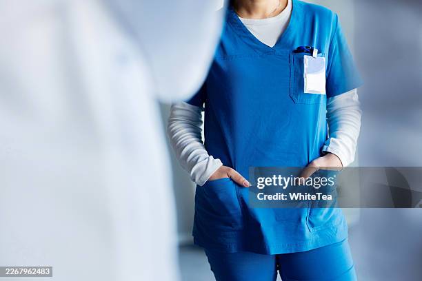 female nurse in blue scrubs standing with hands - name tag stock pictures, royalty-free photos & images