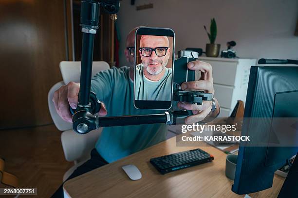 man creating video content with smartphone and rig in home studio - multimedia stockfoto's en -beelden