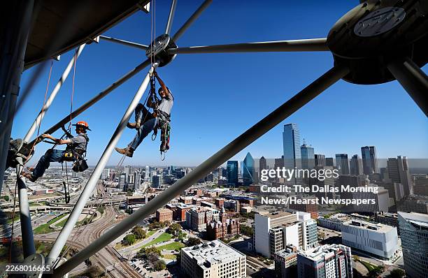 Before the Dallas skyline, rope access technicians Ian Porter and Kain McLaughlin of Highpoint Access scale the lattice-shell structure of Reunion...