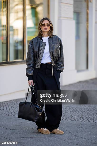 Sophia Geiss wears Apple headphone cables brown sneakers Nubik, black pants Zara, white top black palms, grey leather jacket Acne studio, sunglasses...