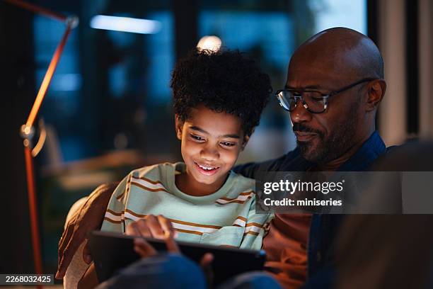 schwarzer vater und sohn abends zu hause mit einem tablet, familienlebensstil-moment - schwache beleuchtung stock-fotos und bilder