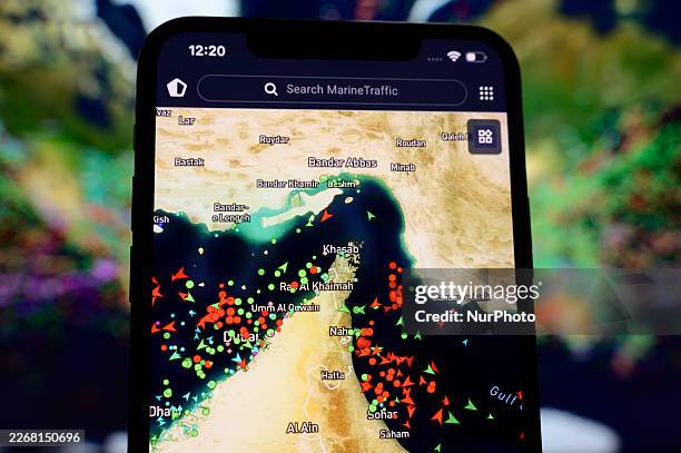 Smartphone screen displaying the MarineTraffic map shows a high concentration of ship beacons in the Strait of Hormuz in Creteil, France, on March...