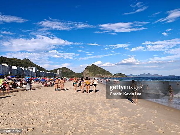 soleada playa de río con costa abarrotada y pan de azúcar en río de janeiro, brasil - playa de copacabana fotografías e imágenes de stock