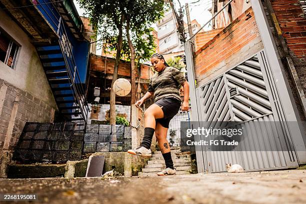 young woman juggles a soccer ball in a community in são paulo - juggling stock pictures, royalty-free photos & images
