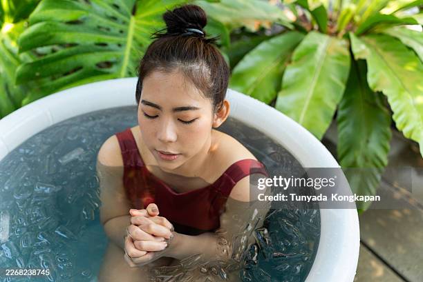 top view of beautiful asian woman practicing outdoor ice bath in cold water for recovery therapy, cryotherapy ritual wellness trend in longevity lifestyle immune support and inflammation relief. - biological process stock pictures, royalty-free photos & images