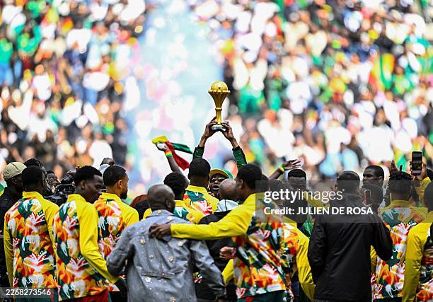 Senegalese musician Youssou N'Dour holds The African Cup of Nations Trophy as Senegal's players gather around him ahead of the international friendly...