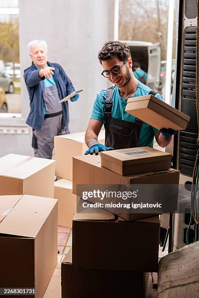 delivery workers coordinating while unloading packages from van - computer loading stock pictures, royalty-free photos & images