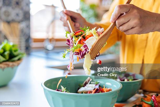 fresh vegetable salad being tossed in bowl during meal preparation - salad stock pictures, royalty-free photos & images