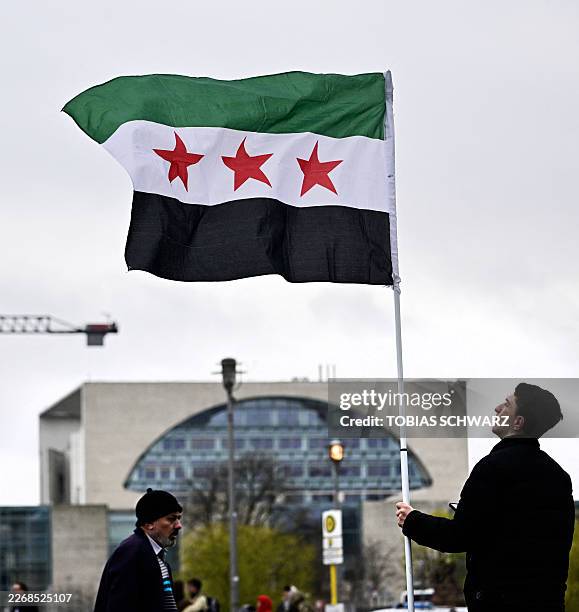 Demonstrator waves the Syrian flag in front of the Chancellery before the meeting between the German Chancellor and Syrian President at the...