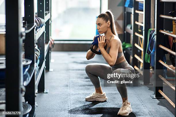 entrenamiento de sentadilla con pesas rusas en un gimnasio. - agacharse fotografías e imágenes de stock