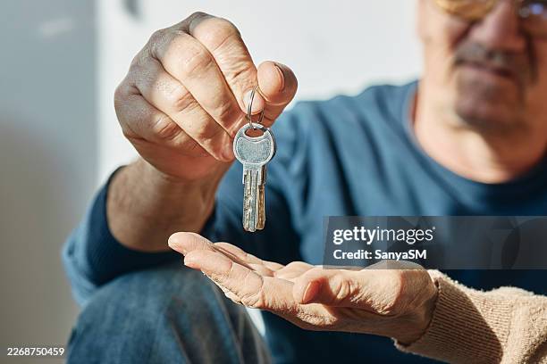 person handing house keys representing new home ownership - uitwisselen stockfoto's en -beelden