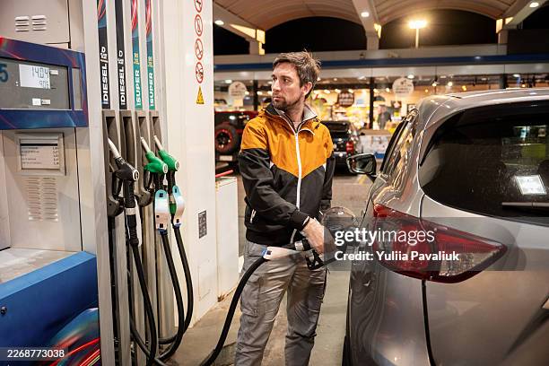 man fueling car at gas station at night - tanken stock-fotos und bilder