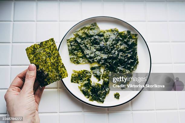 top view of crispy seaweed chips in white bowl, minimalist food photography on light wooden background - nori photos et images de collection