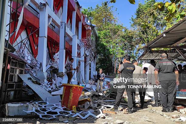 Police officers look at a building of the North Sumatra's National Sports Committee of Indonesia damaged following a severe 7.4-magnitude offshore...