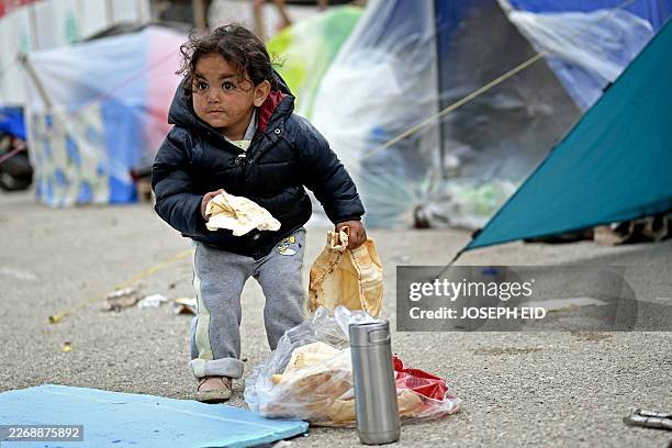 Displaced young girl holds a loaf of bread at an unofficial camp for displaced people on Beirut's waterfront area on April 2, 2026. Lebanon was drawn...