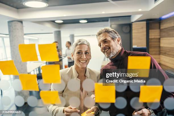 des collègues d’affaires collaborant sur la stratégie à l’aide de post-its - réunion du personnel photos et images de collection