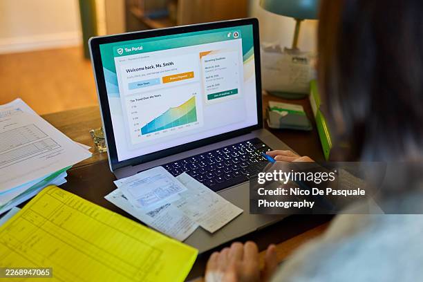 senior woman using online tax portal on laptop at home - long receipt stock pictures, royalty-free photos & images