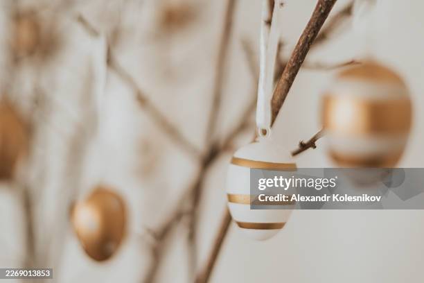 golden striped easter eggs hanging on branches - march month stock pictures, royalty-free photos & images