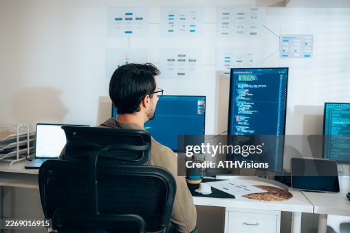 Young Hispanic male software developer working at coding workstation Young Hispanic male software developer working at coding workstation
