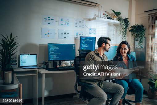 Hispanic software engineer and web developer collaborating at workstation Hispanic software engineer and web developer collaborating at workstation