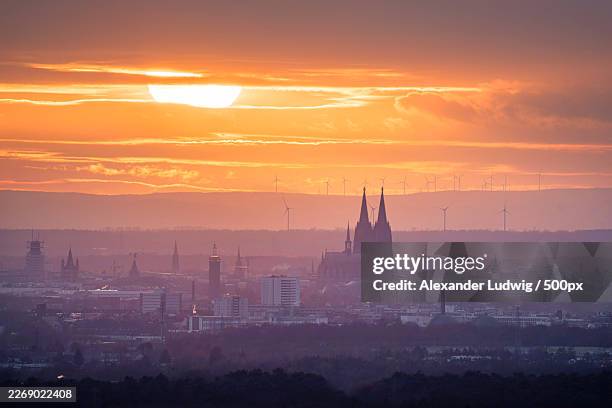 cologne cathedral and city skyline at sunset with wind turbines in the distance,germany - kölner dom stock-fotos und bilder