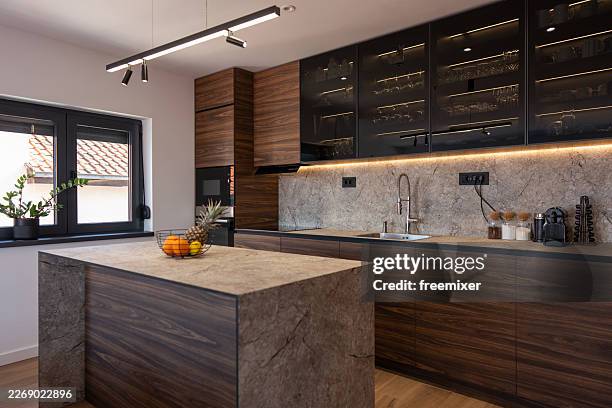 modern kitchen interior with marble island, dark wood cabinets and integrated appliances - walnut wood stock pictures, royalty-free photos & images