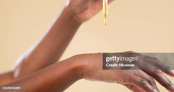 close-up of hand applying facial oil with dropper during natural skincare beauty routine - facial oil stock pictures, royalty-free photos & images