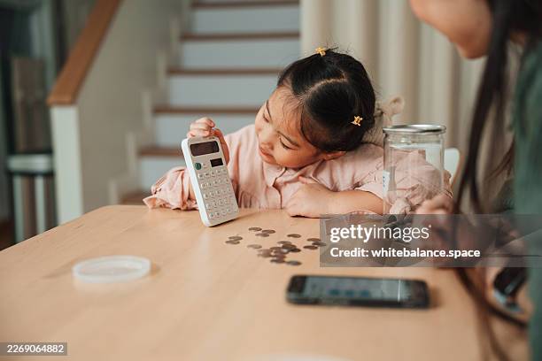 mom teaching her daughter how to count coins and understand the value of saving - financial literacy stock pictures, royalty-free photos & images