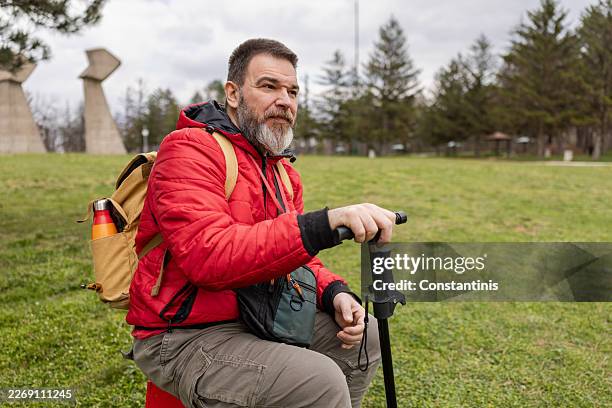 male with multiple sclerosis with a stick in hand sitting in nature - multiple sclerose stockfoto's en -beelden
