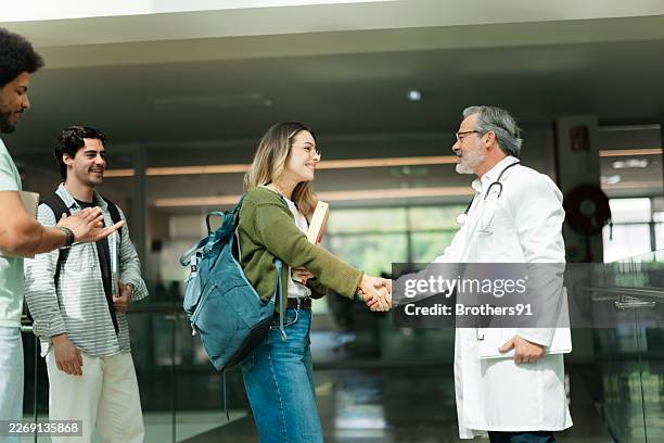 medical student shaking hands with a doctor professor at university - dedication imagens e fotografias de stock