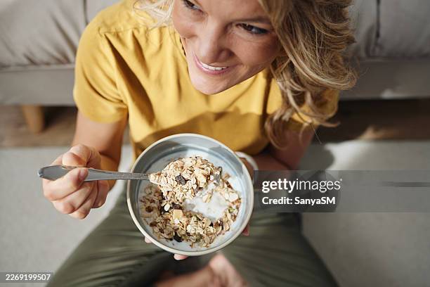 donna sorridente che mangia colazione sana con muesli e yogurt - cereali da colazione foto e immagini stock