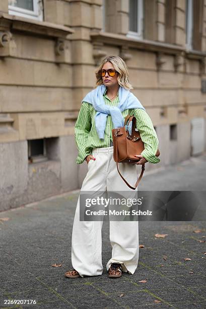 Julia Kammerer is seen wearing a green and white striped button down blouse with a pointed collar and a chest pocket from JJXX; a baby blue knit...