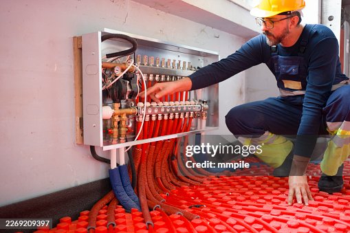 Engineer Inspecting Heating System with Control Panel and Pipes Engineer Inspecting Heating System with Control Panel and Pipes