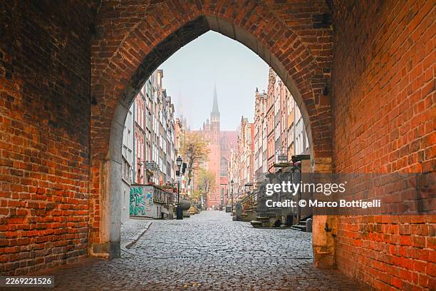 gothic brick gateway framing the cobblestone long market, old town gdańsk, poland - cobblestone stock pictures, royalty-free photos & images