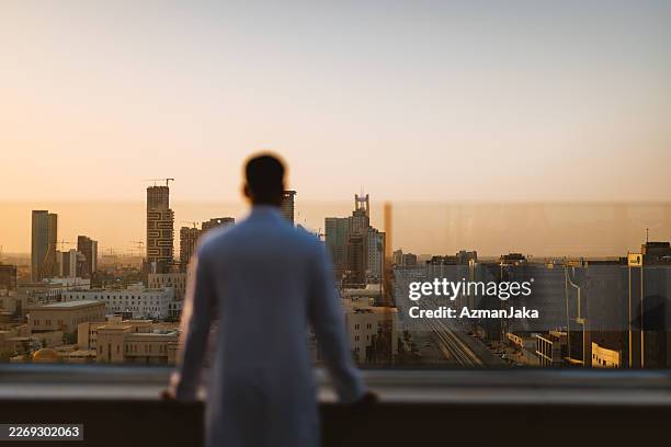 middle eastern man observing riyadh skyline at dusk - saudi arabia skyline stock pictures, royalty-free photos & images