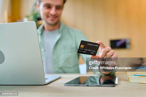 man holding credit card for secure online payment - équipement à base de papier photos et images de collection