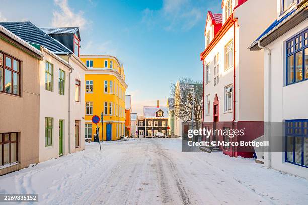 snow-covered street lined with colourful houses in winter, reykjavik, iceland - reykjavik stock pictures, royalty-free photos & images