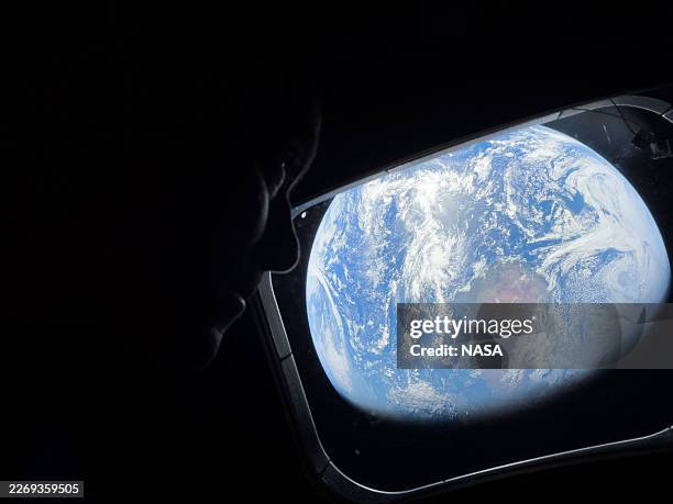 In this handout image provided by NASA, NASA astronaut and Artemis II Commander Reid Wiseman peers out of one of the Orion spacecraft's main cabin...