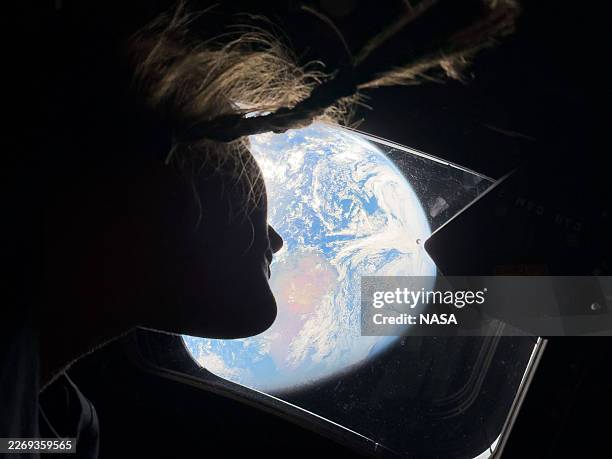 In this handout image provided by NASA, NASA astronaut and Artemis II mission specialist Christina Koch peers out of one of the Orion spacecraft's...