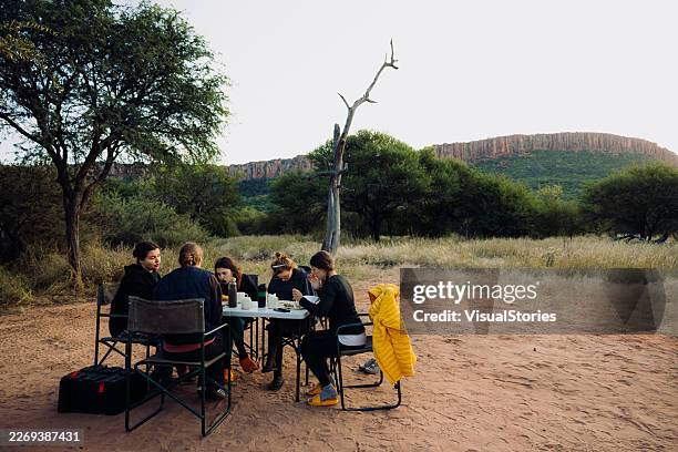 group of women enjoying breakfast camping in african savannah - namibia stock pictures, royalty-free photos & images