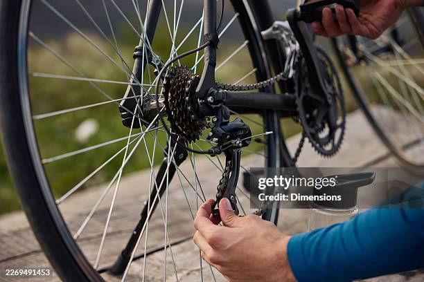 cyclist performing bicycle chain maintenance and derailleur repair - bicycle chain stock pictures, royalty-free photos & images