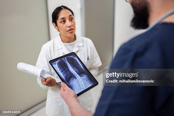 doctors reviewing chest x-ray on tablet in hospital corridor - radiology technician stock pictures, royalty-free photos & images